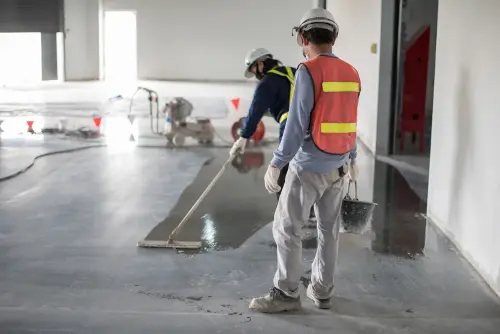Construction workers leveling freshly poured concrete floor.