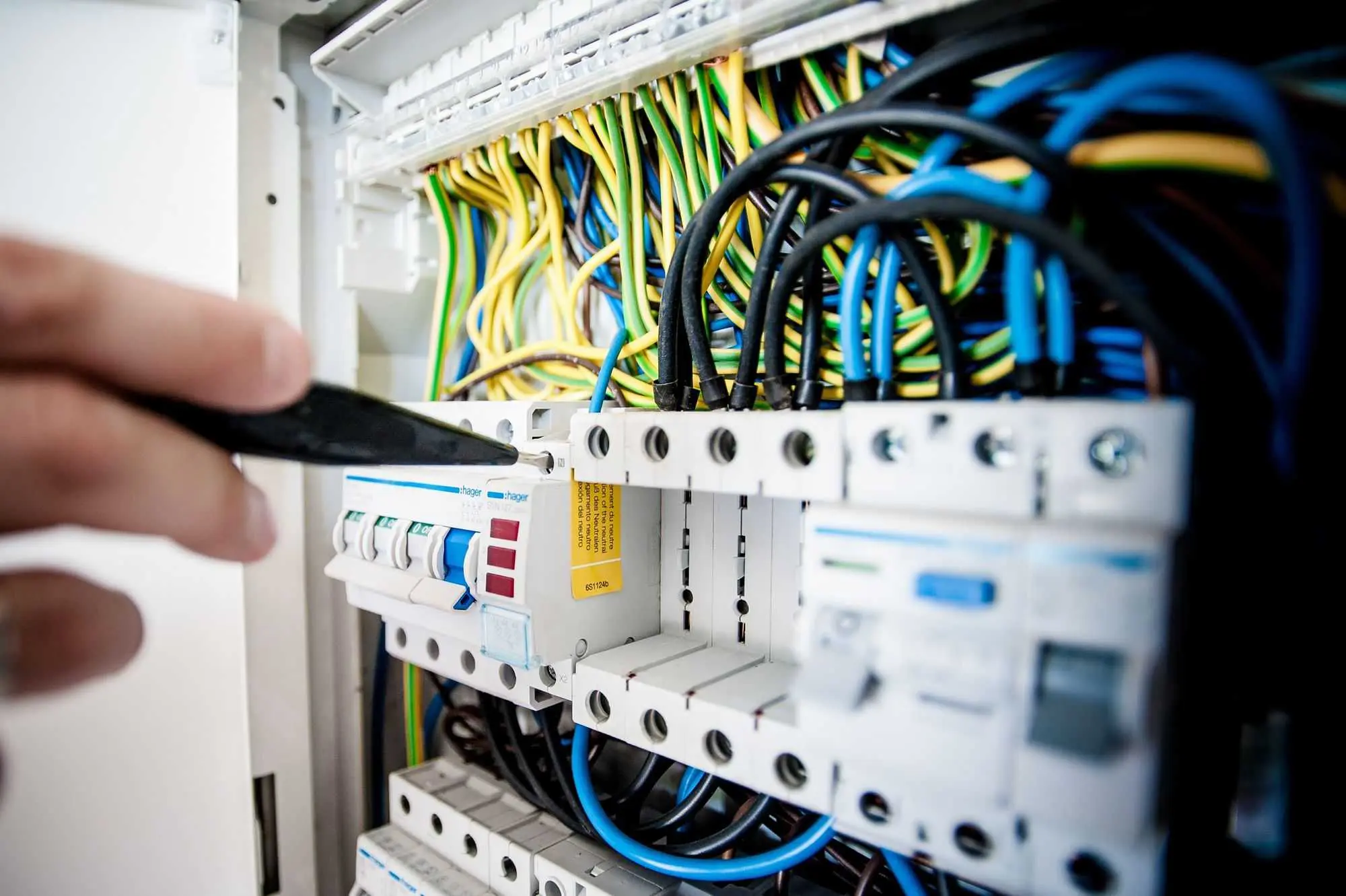 A technician adjusting circuit breakers in an electrical panel.