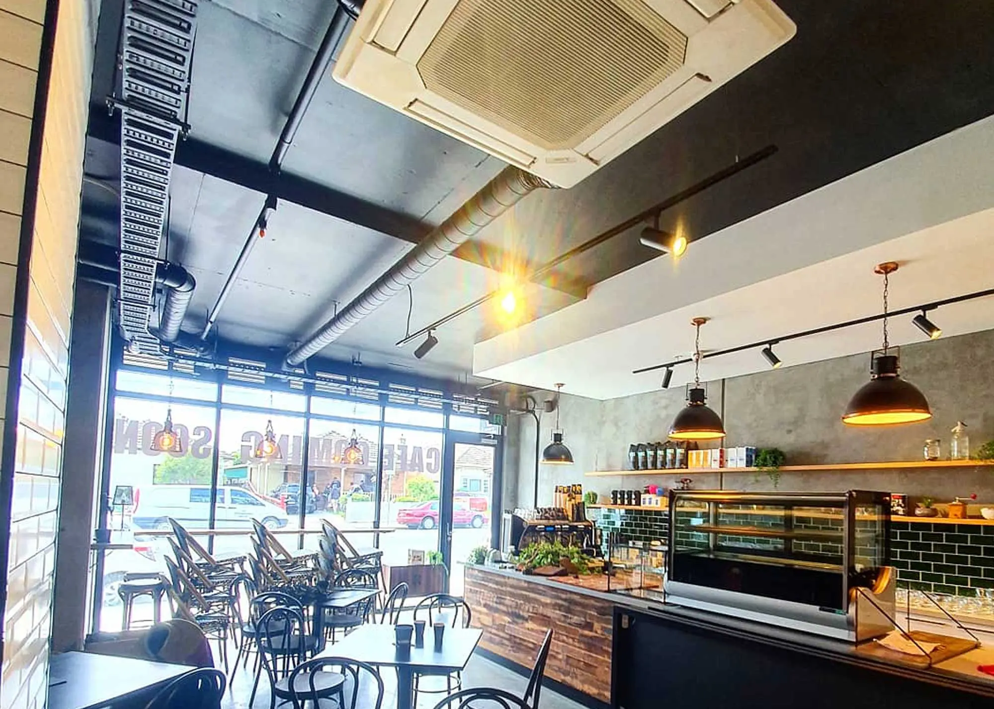 Cozy café interior with modern decor and a view through large windows.