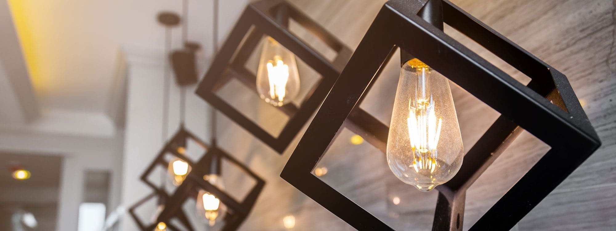 Stylish pendant lights in geometric black frames illuminate a modern space.