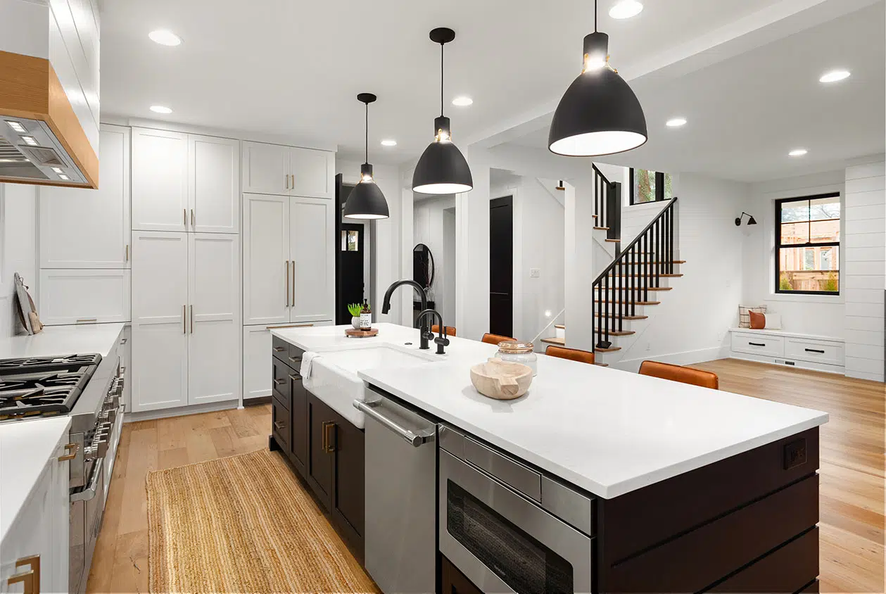 Modern kitchen with white cabinetry, black accents, and pendant lights.