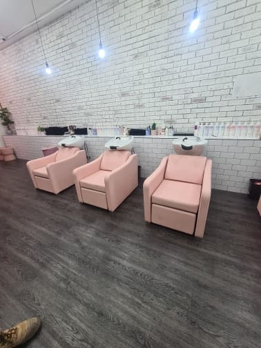 Three pink salon chairs in a modern hair salon interior.